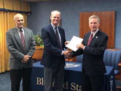 Diversified Energy Corporation President/CEO Paul Nester (center) presents a gift deed to Bluefield State College President Robin Capehart (right), granting and releasing to BSC two parcels of real estate adjacent to new student housing now under construction on BSC’s campus.  BSC alumnus Jim Shockley (left), Company Chief Operating Officer/VP, also took part in the program.
