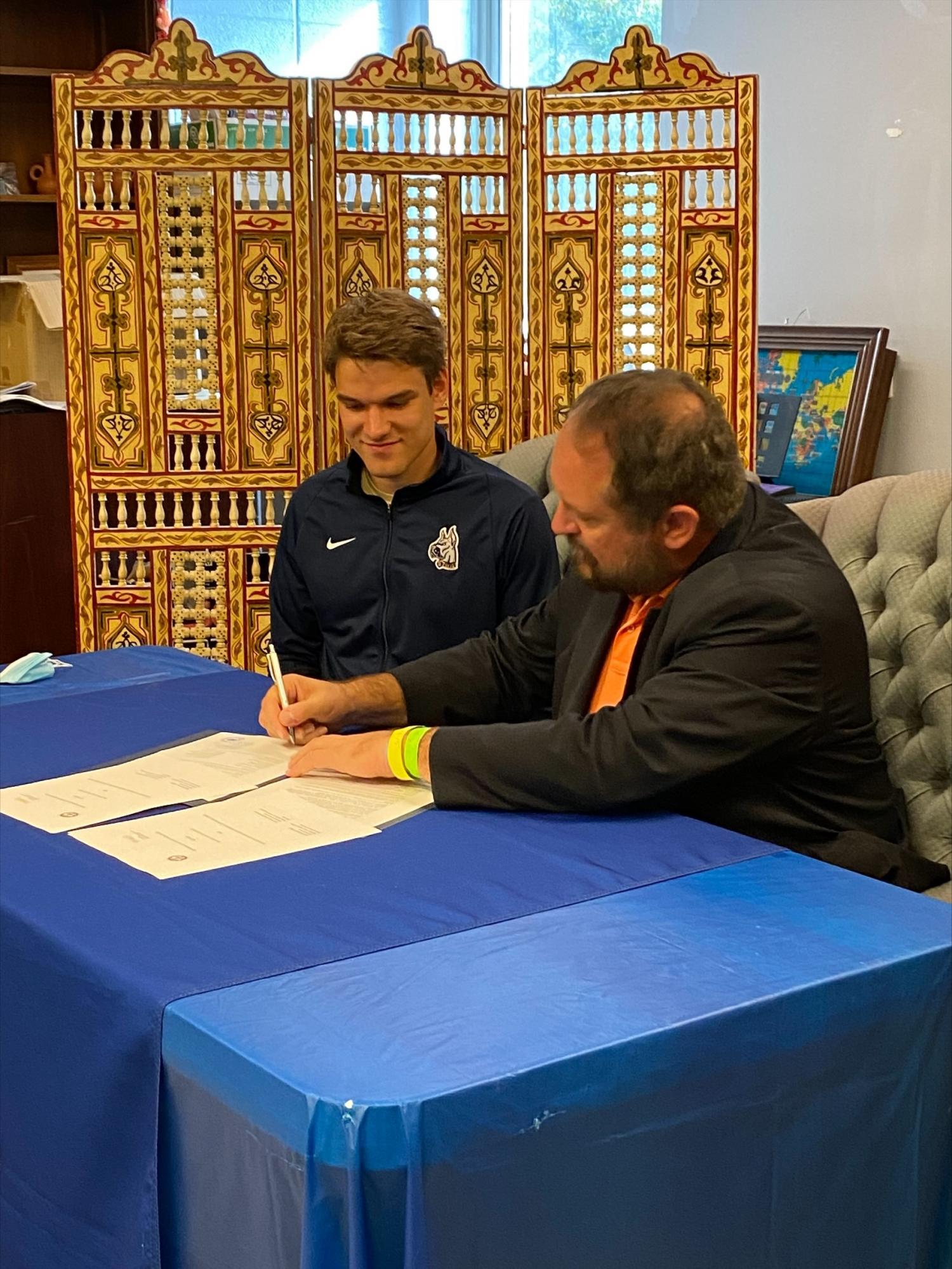 Bluefield State College student Theodor Schell (left) observes as Dr. Ted Lewis, BSC provost signs a Memorandum of Agreement with the University of Applied Sciences of Wurzburg-Scheinfurt FHWS), Germany.  The MOU promotes student and faculty exchanges, collaborative faculty research, and information exchanges between Bluefield State and FHWS.